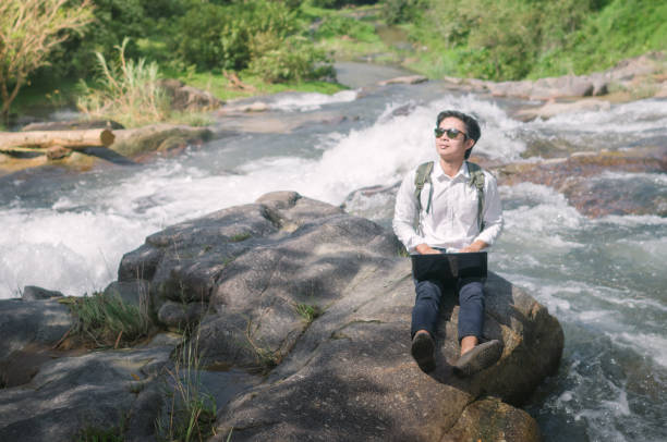istock Businessman with backpack and laptop and phone at  waterfall  the forest. 641864938