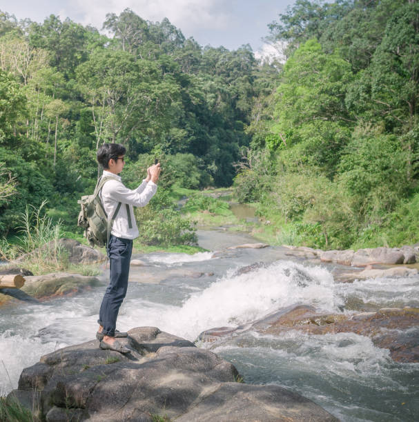 istock Businessman with backpack and laptop and phone at  waterfall  the forest. 641865180