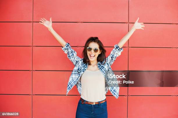 Happy Girl With Arms Raised Against Red Wall Stock Photo - Download Image Now - Women, One Woman Only, Happiness