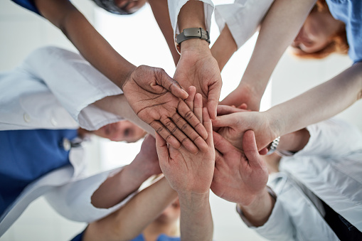 Low angle shot of a group of medical practitioners joining their hands together in unity