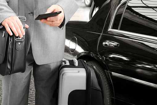 Traveling Businessman with His Luggage Using Phone