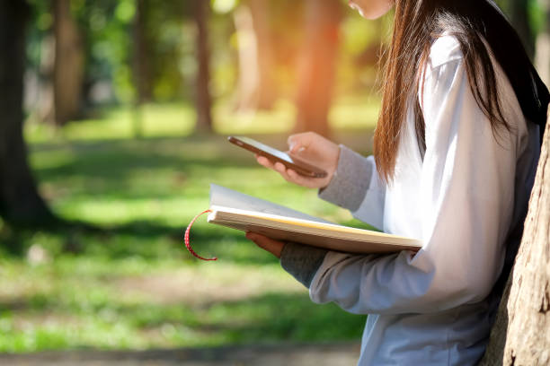 istock Girls  playing smart phone and book in hand. 641868758