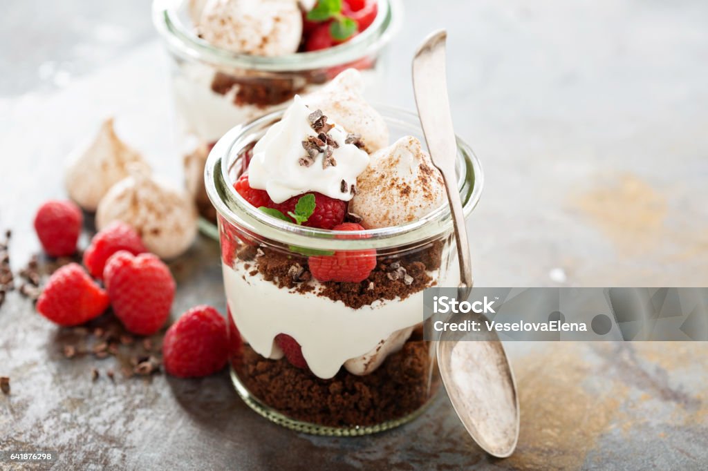 Layered dessert with chocolate cake and whipped cream Layered dessert with chocolate cake, whipped cream and raspberry in a jar Jar Stock Photo