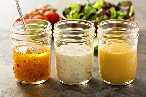 Variety of homemade sauces and salad dressings in mason jars including vinaigrette, ranch and honey mustard