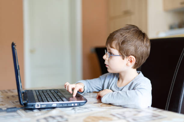 istock kid boy with glasses making preschool homework on computer 641878078