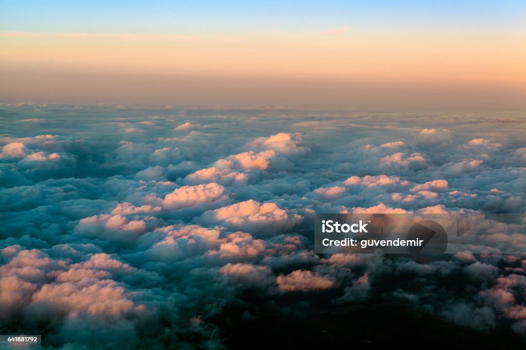 Above the clouds at sunset Aerial view of clouds from a passenger airplane over the sky at sunset Above Stock Photo