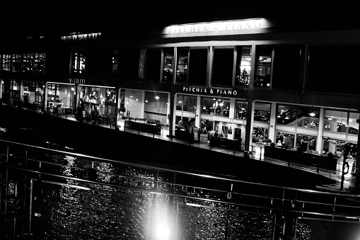 Lighting on the water in the marina and wharf areas in central Bristol. in the background are pubs and restaurants and in the foreground are some leisure craft moored.