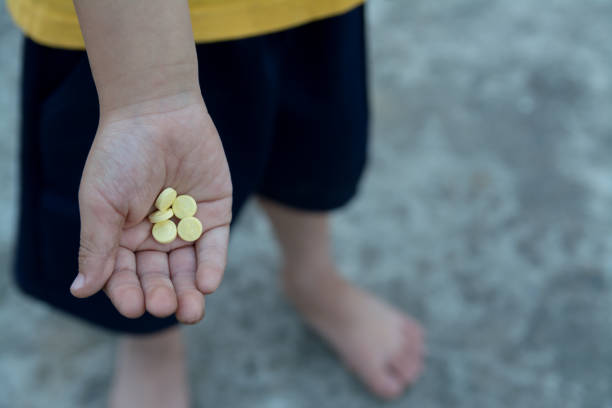 yellow round pill, vitamin in dirty children hand stock photo