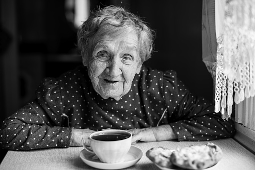 Elderly woman drinking tea. Black and white portrait.