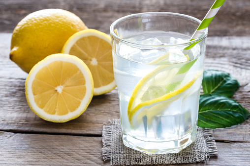 Glass of water with fresh lemon juice on the wooden table