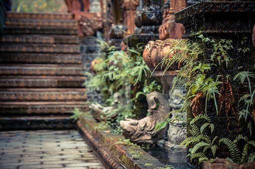 Ancient park alley with old column overgrown with tropical plants in Thailand