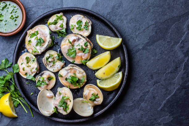 istock Raw clams with lemon, herbs and white wine, slate background 641901474