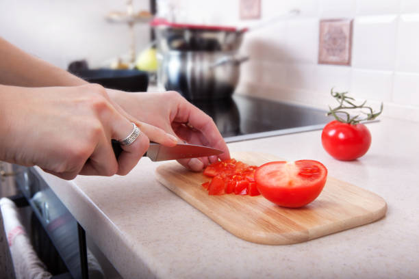 istock woman cuts tomatoes with a knife on the kitchen table 641905082