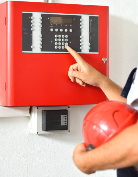 Engineer checking the fire alarm system Firefighter with hard hat at job site. Examining equipment. fire alarm photos stock pictures, royalty-free photos & images
