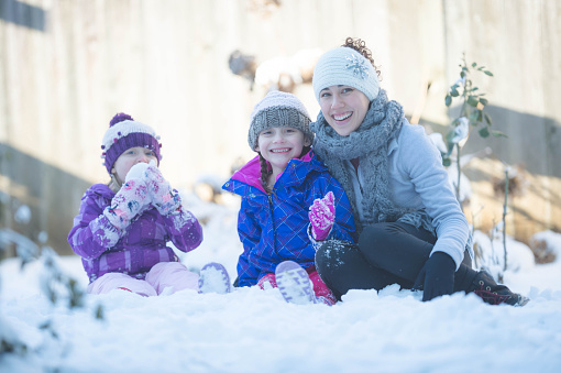 Mom Playing With Young Girls on Snowy Neighborhood Street