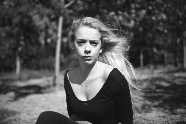 Monochrome portrait of blonde young woman on gray background