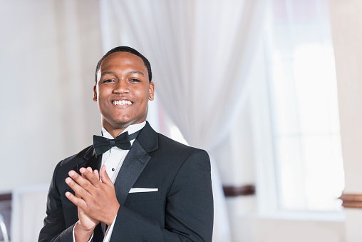 A young black Hispanic man wearing a tuxedo. He is dressed for a special event, perhaps a wedding or prom.