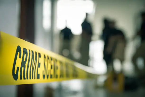 Photo of crime scene tape with blurred forensic in cinematic tone