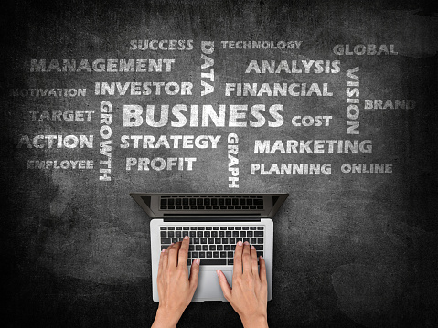 Businesswoman using laptop with concept of successful business strategy on blackboard