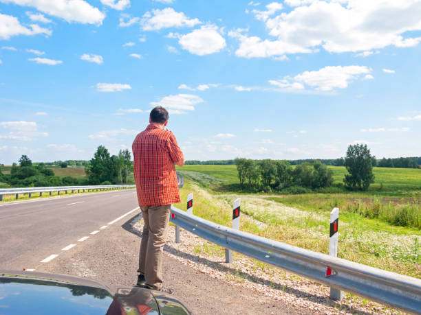 Tall man in check shirt stands back before highway turn