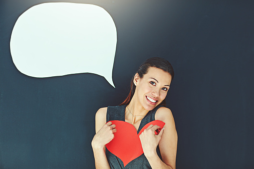 Portrait of a young woman posing with a heart against a gray background