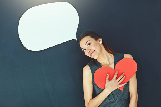 Portrait of a young woman posing with a heart against a gray background