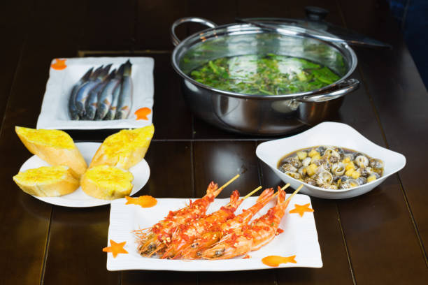 Set of Vietnamese seafood with Barbecue tiger shrimps, bread slide, Stir-fried snail with tamarind, and hot pot with fish