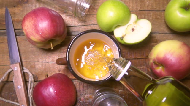 From the bottle pours fresh apple juice in glass. Rustic style Slow motion