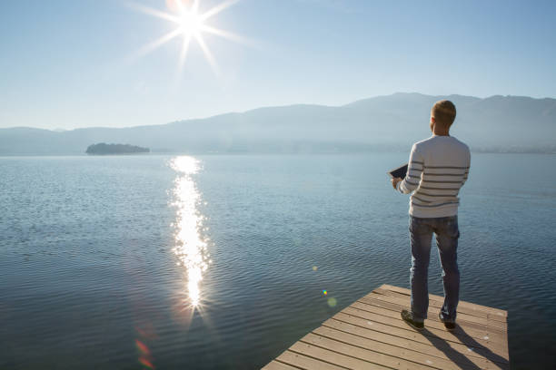 istock Young man relaxing on lake pier with digital tablet 641943736