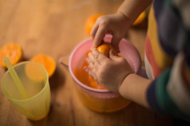 pequeno filho de preparar frescas caseiras sumo de laranja - freshly squeezed orange juice imagens e fotografias de stock