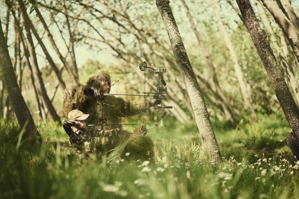 Shot of a father and son in camouflage hunting with bows and arrows in the woods