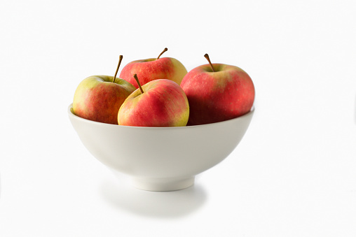 Diet of apples for less weight and healthy living.  bowl of four red apples on a white background.
