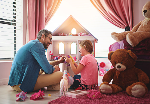 Shot of a father and daughter playing with a dollhouse together