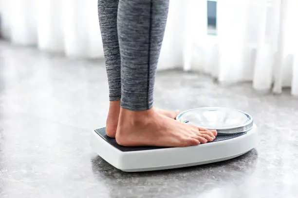 Photo of Young healthy girl on home scales