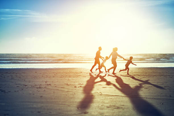 el sol de verano aporta diversión familiar - holding hands child silhouette family fotografías e imágenes de stock