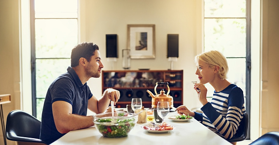 Shot of a young couple having a meal together at the dining table