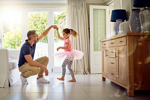 Shot of a happy father and daughter dancing together at home