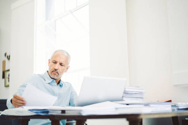 istock Businessman reading document at desk in office 641968522