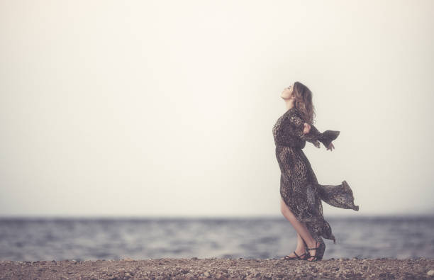 side view of young woman in summer day enjoying the freedom feeling on the beach.