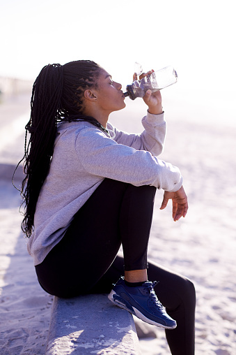 Full length shot of an attractive young woman getting a drink during her workout