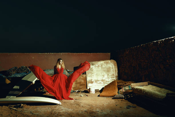 fashion shot of glamour woman in the night time wearing red dress, posing with it flying around her.