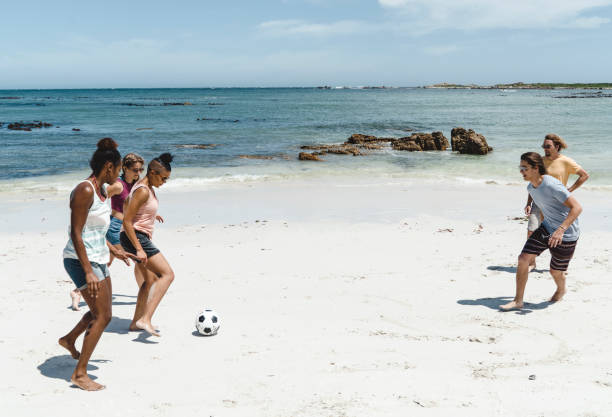 istock Happy friends playing soccer on shore at beach 641972408