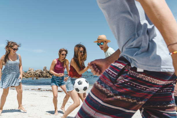 istock Friends playing soccer on shore at beach 641972452