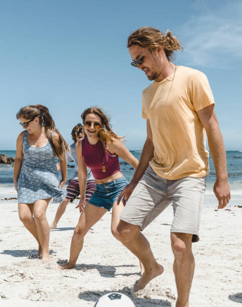 istock Men and women playing soccer on shore at beach 641972466