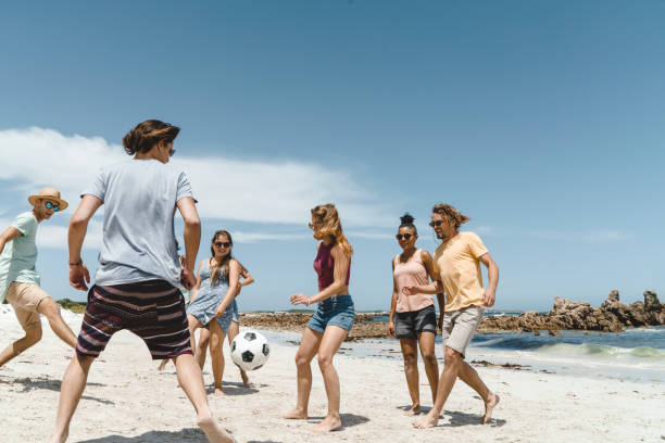istock Happy friends playing soccer on shore 641972500