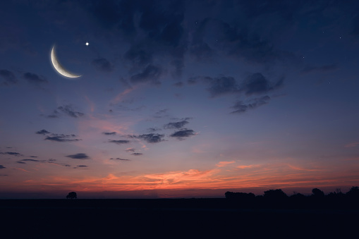 Crescent moon with pink sky at sunset.