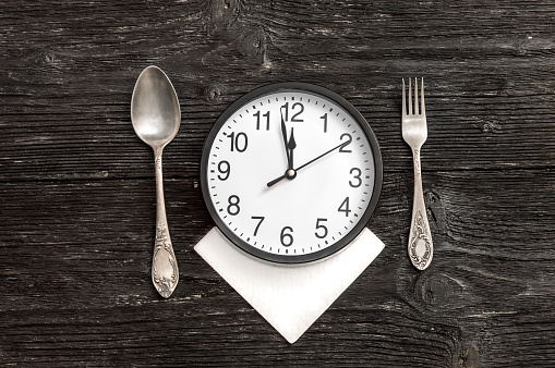 Clock on serviette with fork and spoon.Top view. Time to eat.