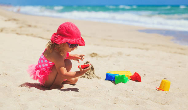 istock cute little girl play with sand on beach 641992928