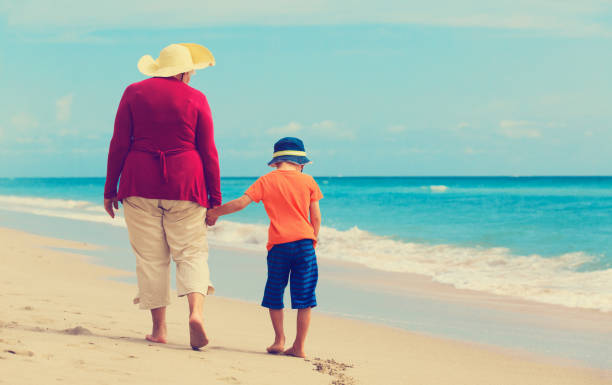 istock Happy grandmother with grandson walk at beach 641993358