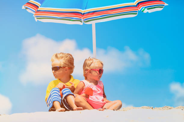 istock little boy and girl site under parasol on summer beach 641993778